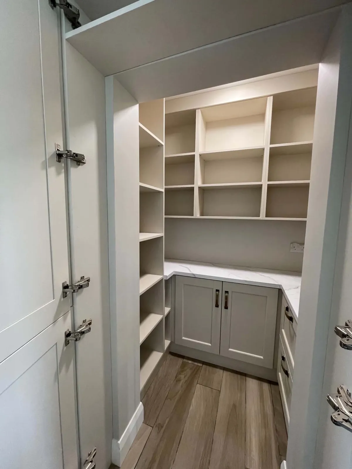 Clean fitted pantry with empty shelves, cabinets, worktop and floor