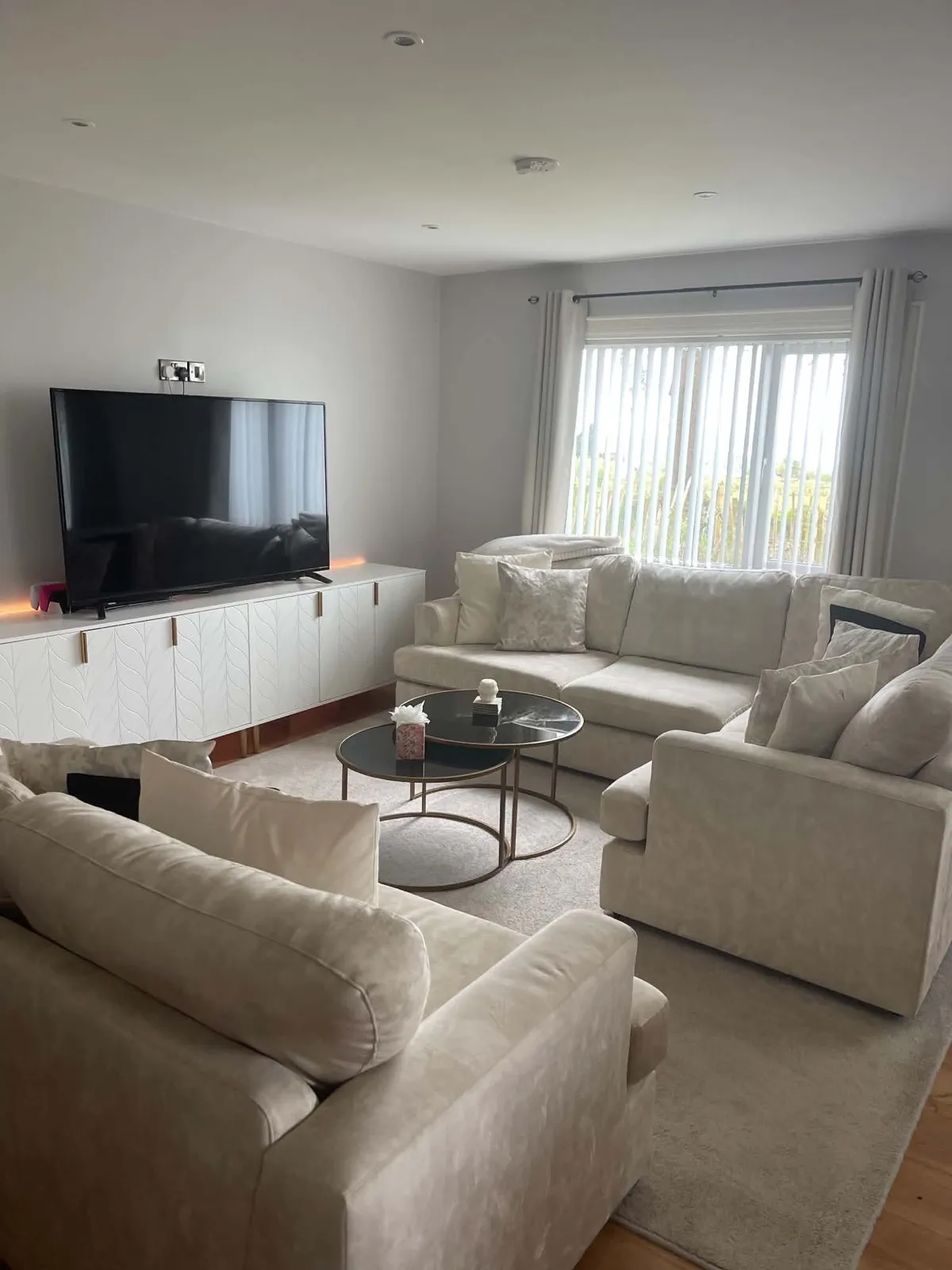 The same living room after cleaning and resetting, with clear tables and neatly arranged seating