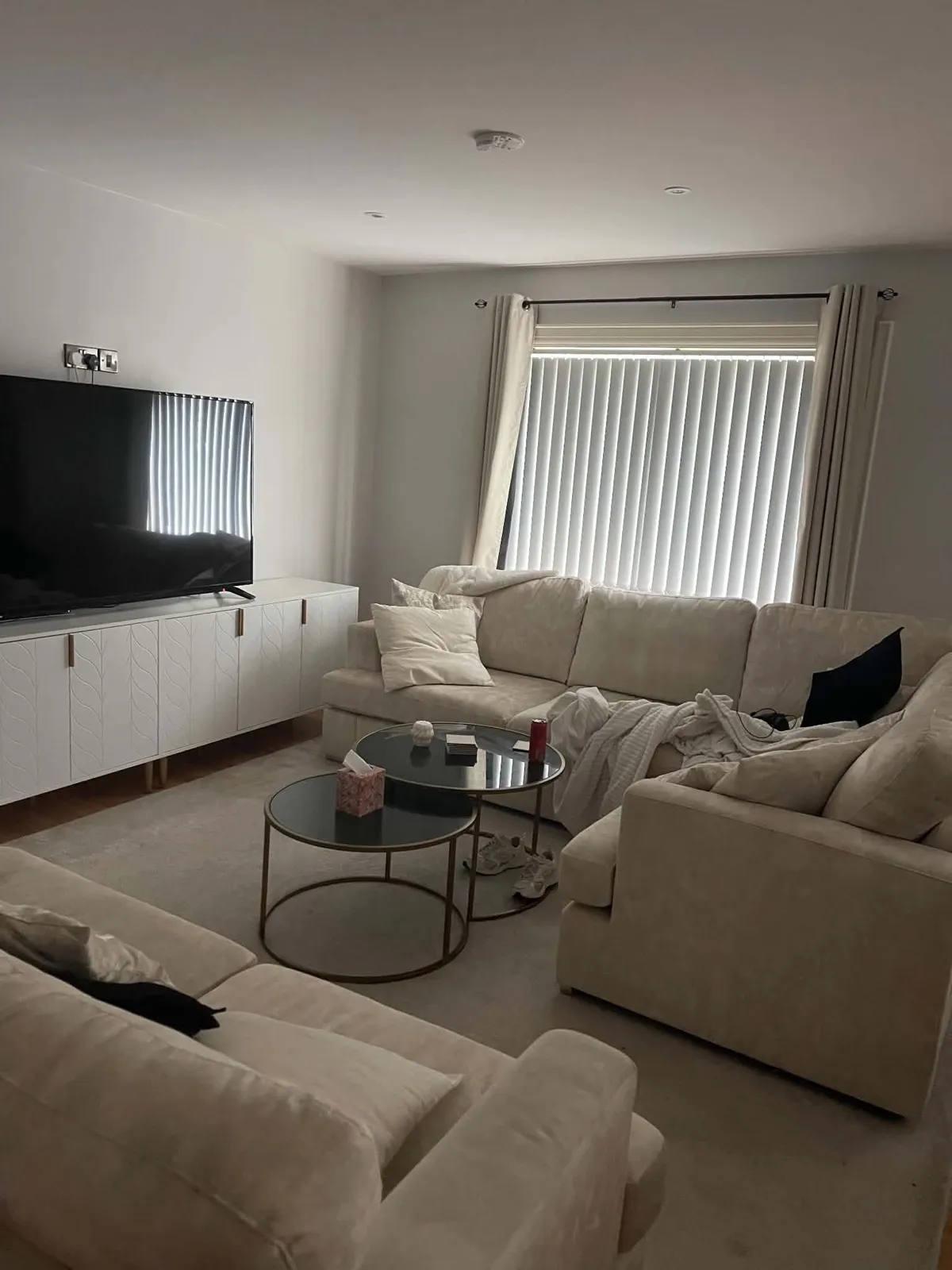 Living room before cleaning and resetting, with clutter across the seating and tables