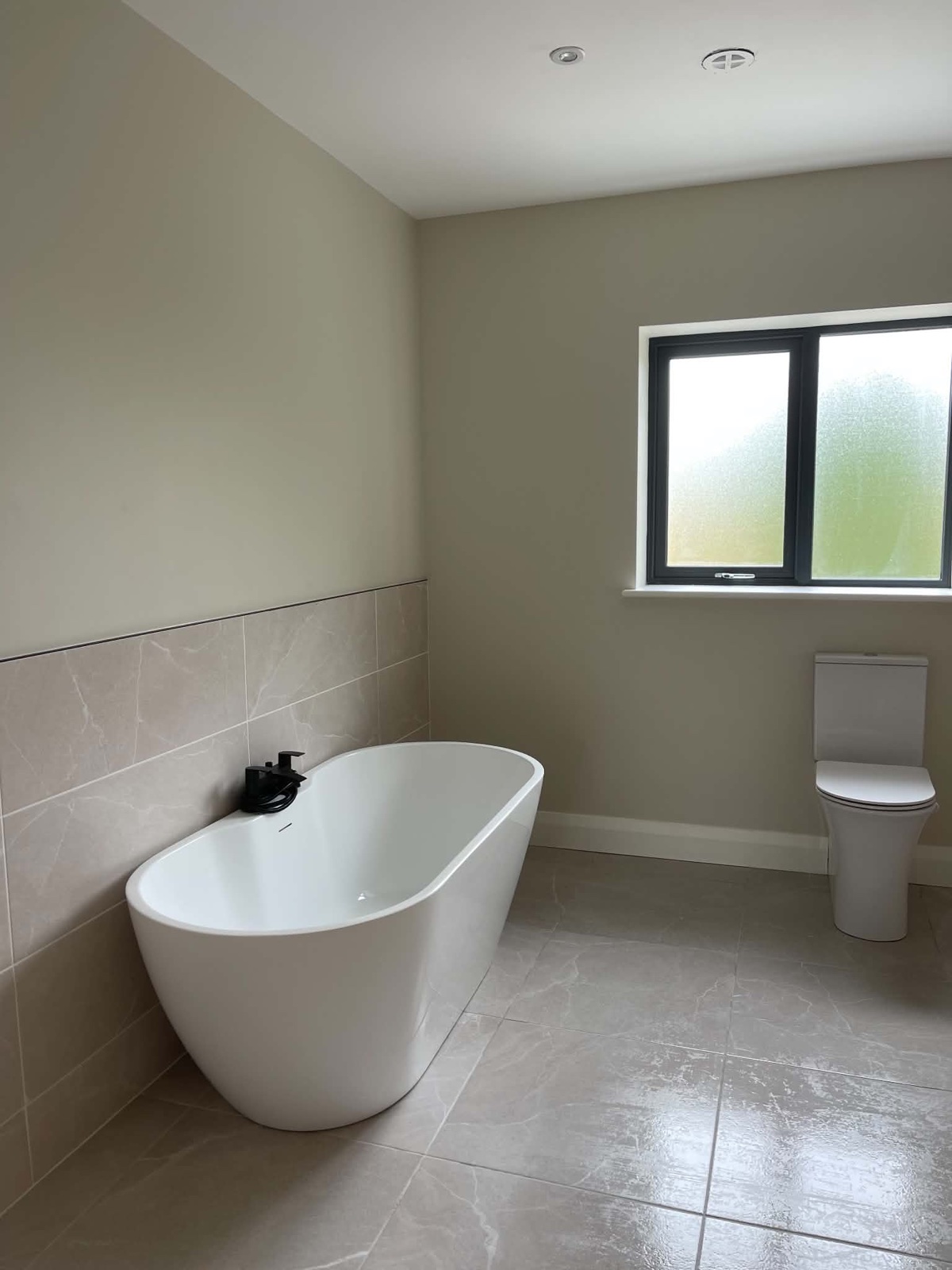 Finished bathroom after cleaning with clean bath, toilet and polished tiled floor