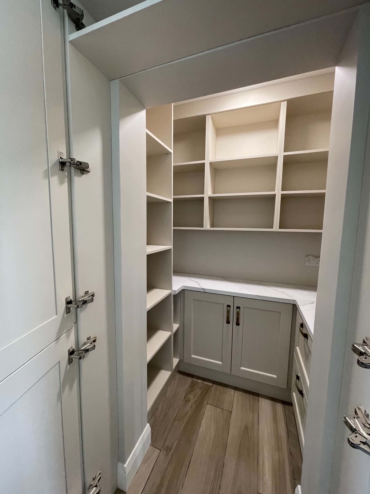 Clean fitted pantry with empty shelves, cabinets, worktop and floor