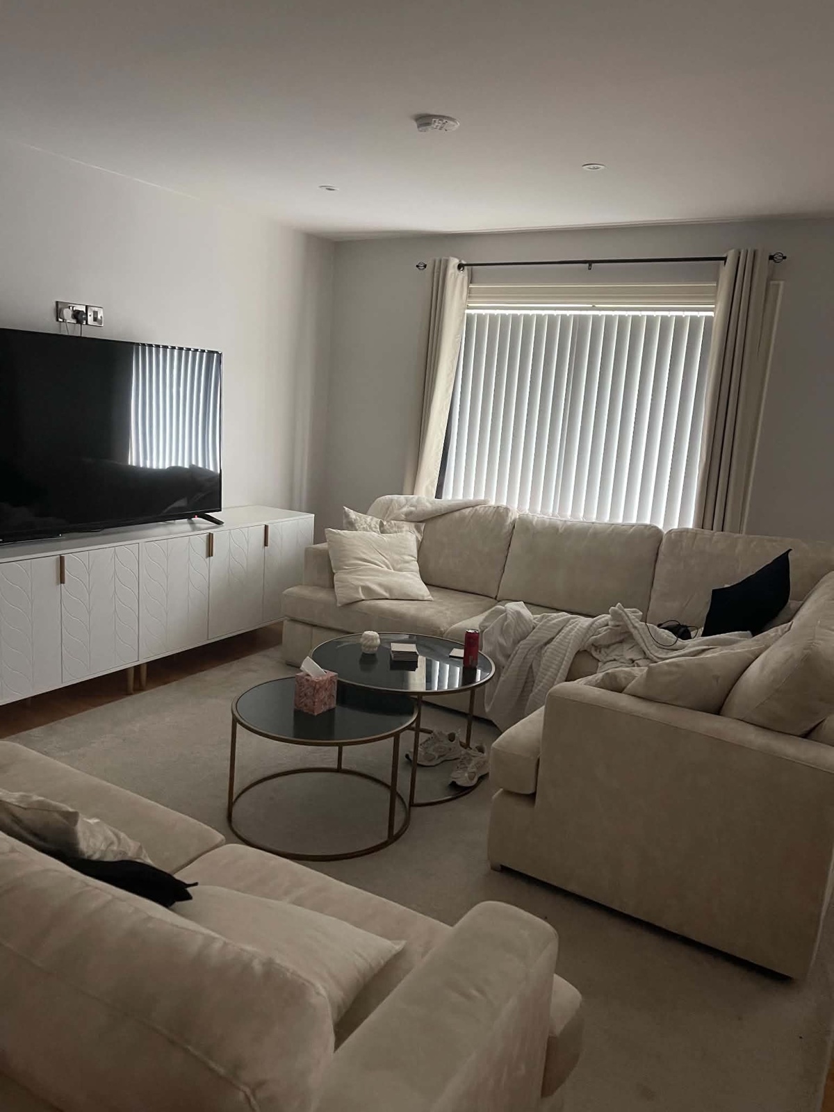 Living room before cleaning and resetting, with clutter across the seating and tables