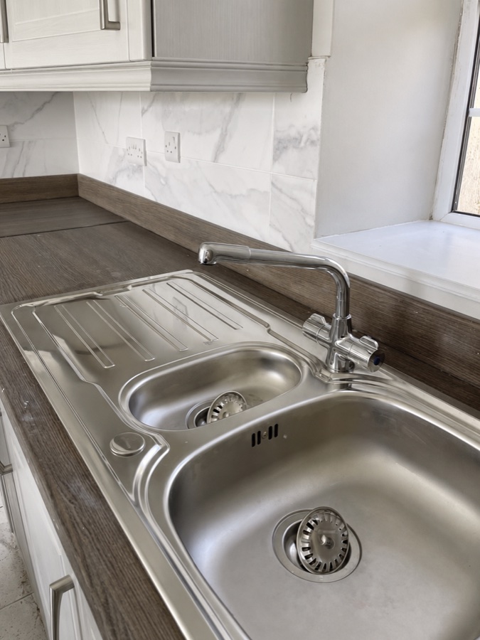 The same kitchen sink and draining board after cleaning