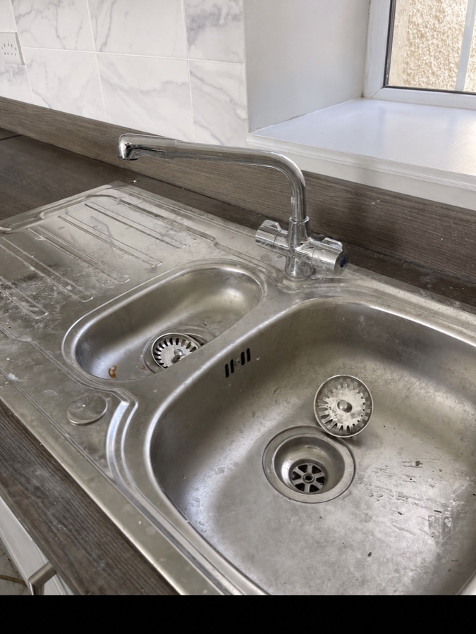 Kitchen sink and draining board before cleaning, showing marks and residue